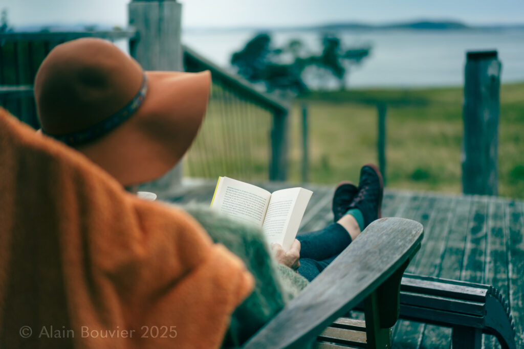 Lifestyle image, A woman reading a book on Bruny island while enjoying the view of her Airbnb