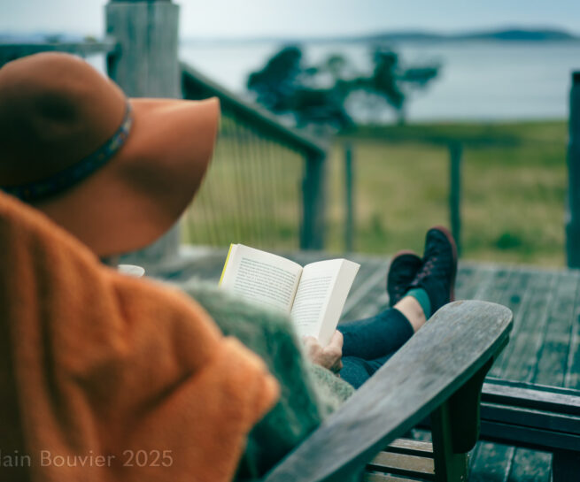 Lifestyle image, A woman reading a book on Bruny island while enjoying the view of her Airbnb